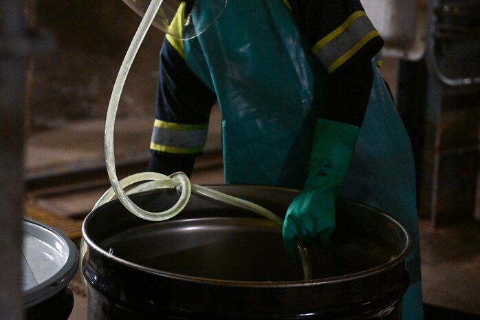 A member in support of Joint Task Force-Red Hill (JTF-RH) guides a drainage line with residual fuel from a spectacle blind into a barrel at the Red Hill Bulk Fuel Storage Facility Jan. 24, 2024, Halawa, Hawaii.