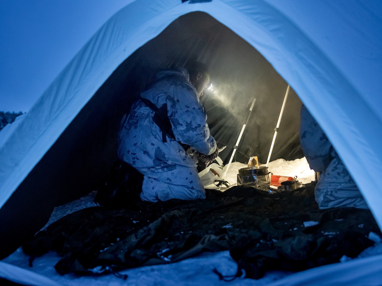 A Marine boils water in a tent.