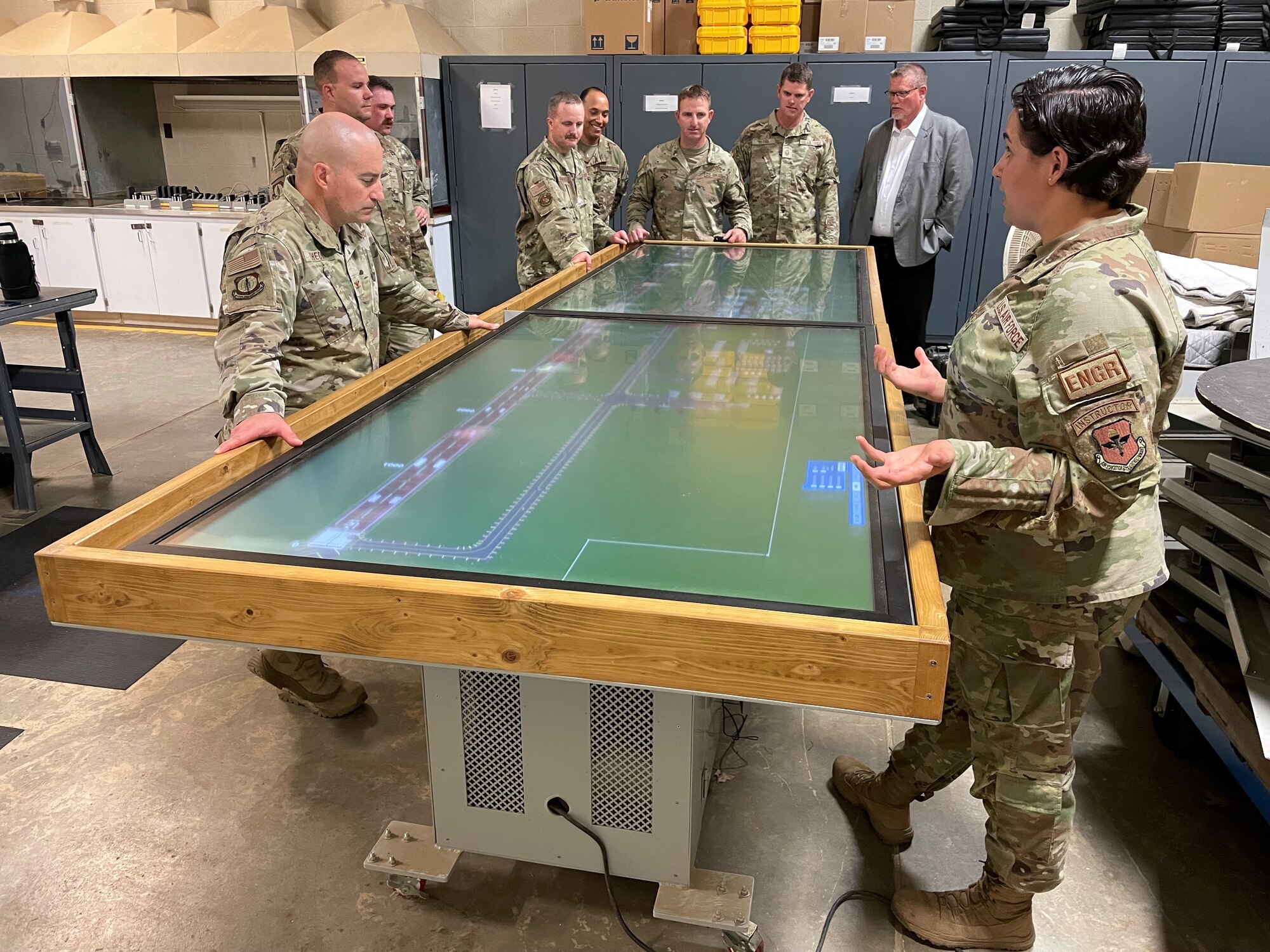 Airmen stand around a table