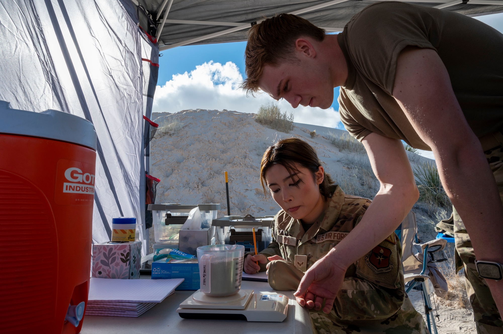 U.S. Air Force Airmen 1st Class Adam Sapp and Kiandra Mandal, 54th Operations Support Squadron weather flight apprentices, measure a sand sample during an exercise at Holloman Air Force Base, New Mexico, Jan. 22, 2024. The 54th OSS provides the base with past, present and future weather observations that are crucial to providing the surrounding squadrons and units with air superiority. (U.S Air Force photo by Airman 1st Class Isaiah Pedrazzini)