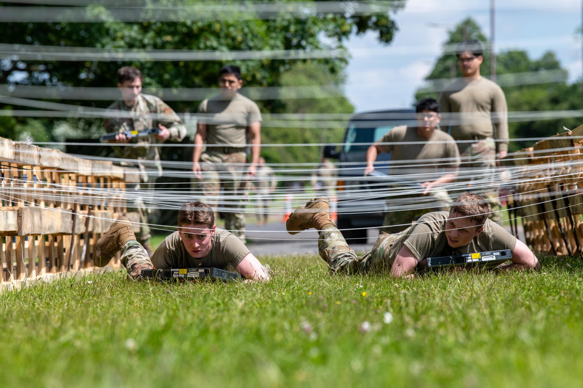 Airmen low crawl while carrying a switch during a Tiger Challenge