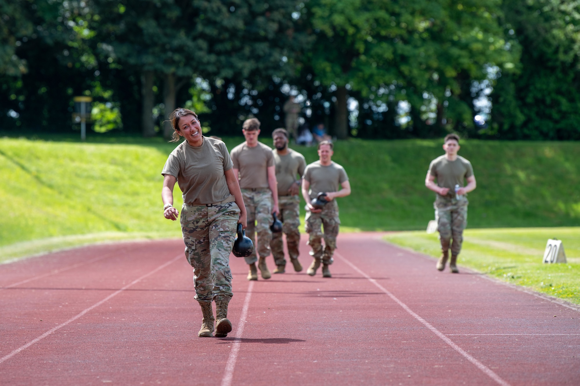 Airmen walk while carrying kettlebells