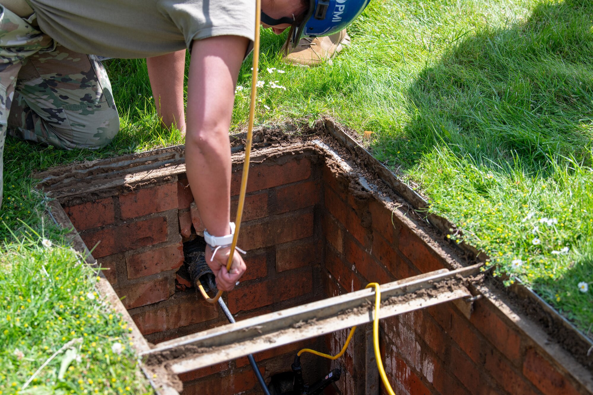 An Airman feeds cable into a manhole during a Tiger Challenge