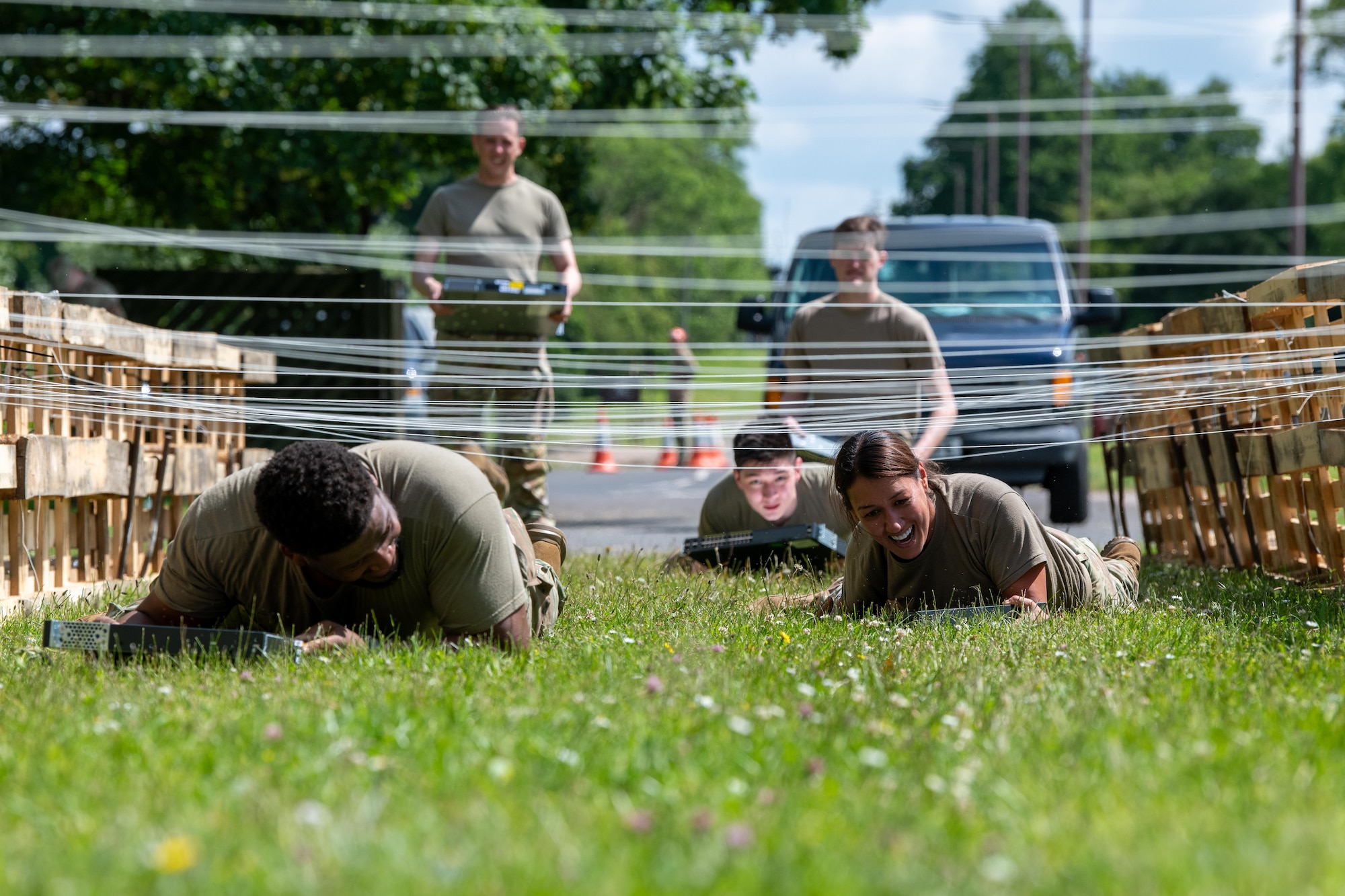 Airmen low crawl while carrying a switch during a Tiger Challenge