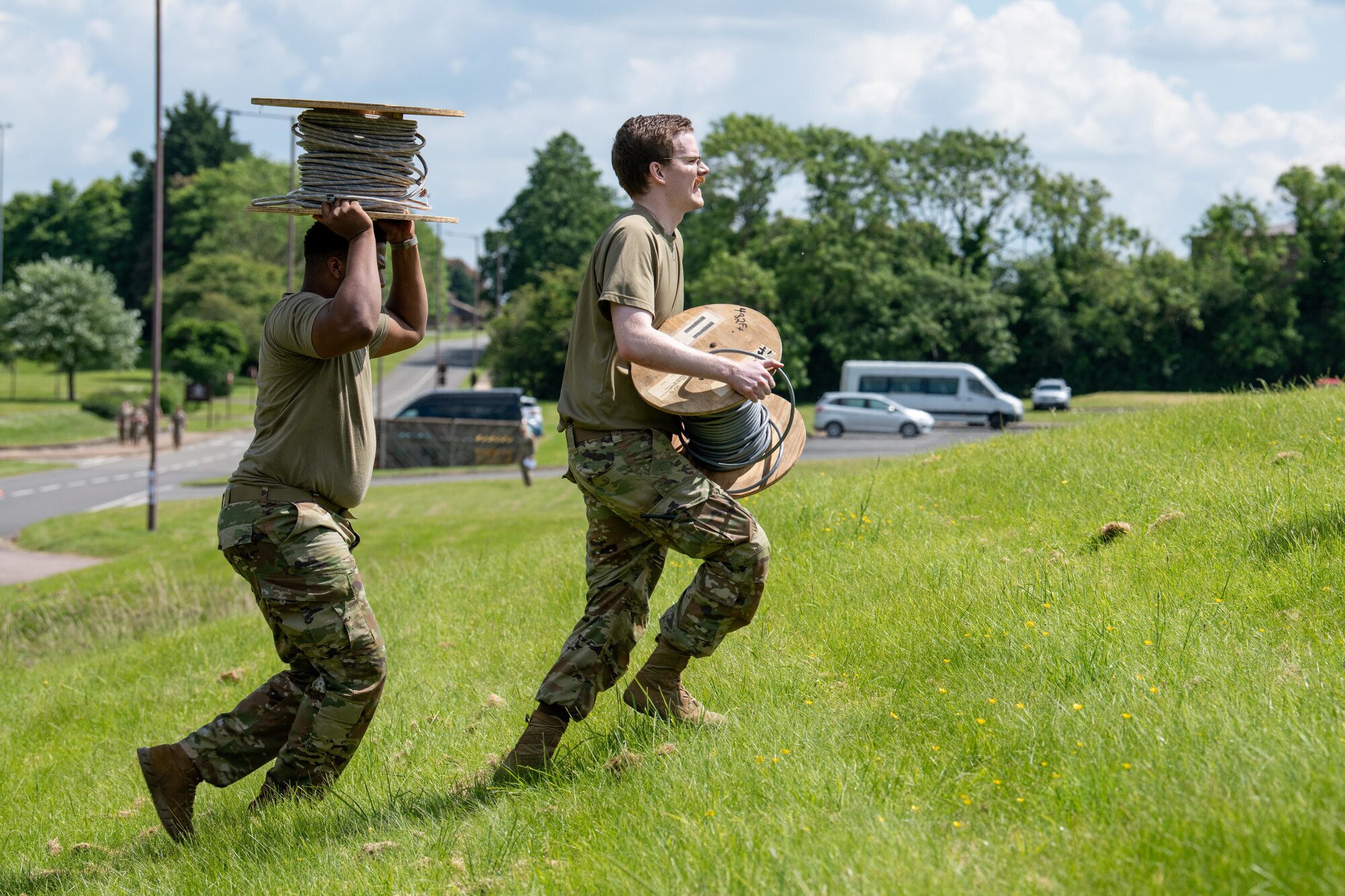 Airmen carry spools of cable uphill during a Tiger Challenge