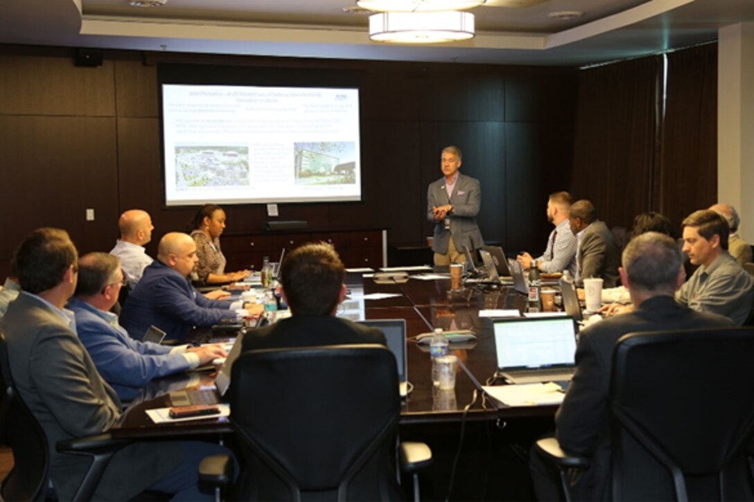 Men around conference table listening to speaker.