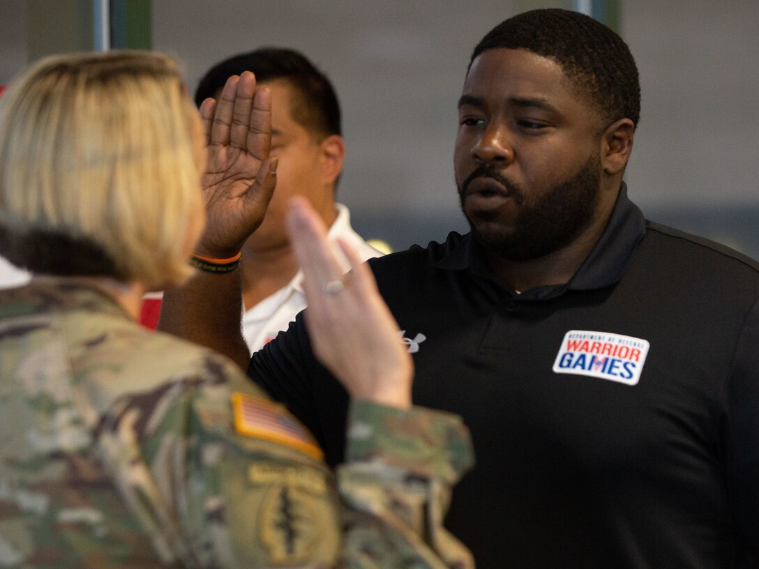 U.S. Army Spc. Darnell Boynton raises his hand and repeats the oath of enlistment while re-enlisting during the 2022 Department of Defense Warrior Games