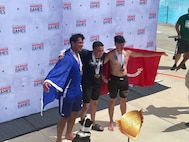 Team Army athlete Sgt. Noah Rydesky, with one of his gold medals in swimming, was flanked by athletes from Team Air Force and Team Marines