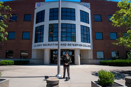 Man in Army uniform standing in front of building.