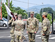 Col. Marc Welde, left, commander of U.S. Army Medical Logistics Command, accepts the unit colors from Lt. Col. Mark Sander, outgoing commander of the U.S. Army Medical Materiel Center-Korea, during a change of command ceremony June 24 at Camp Carroll, Republic of Korea. Welde then passed the colors to the new commander, Lt. Col. Nathan Wagner, center, signifying the transfer of command.