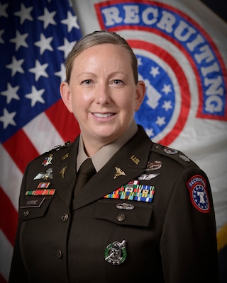 Woman standing in front of two flags wearing U.S. Army uniform.