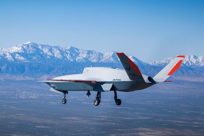 An autonomous Air Force aircraft flies with snow-capped mountains visible in the distance.