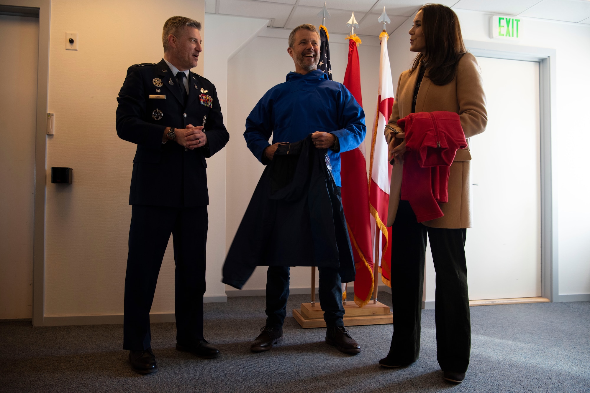From the left, U.S. Space Force Col. Jason Terry, 821st Space Base Group commander, King Frederik X, King of the Kingdom of Denmark, and Queen Mary, Queen of the Kingdom of Denmark, smile together after receiving gifts from Terry on behalf of the Pituffik Space Base personnel at Pituffik SB, Greenland, June 29, 2024. King Frederik X and wife Queen Mary made a stop to Pituffik SB while on their way to the village of Qaanaaq. (U.S. Space Force photo by 1st Lt. Danielle Rose)