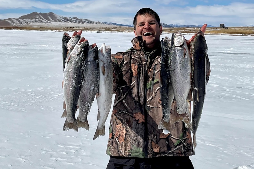 A person holds a line of fish for the camera.