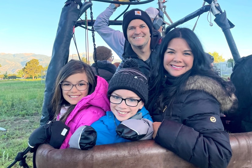 A family smiles from a hot air balloon.