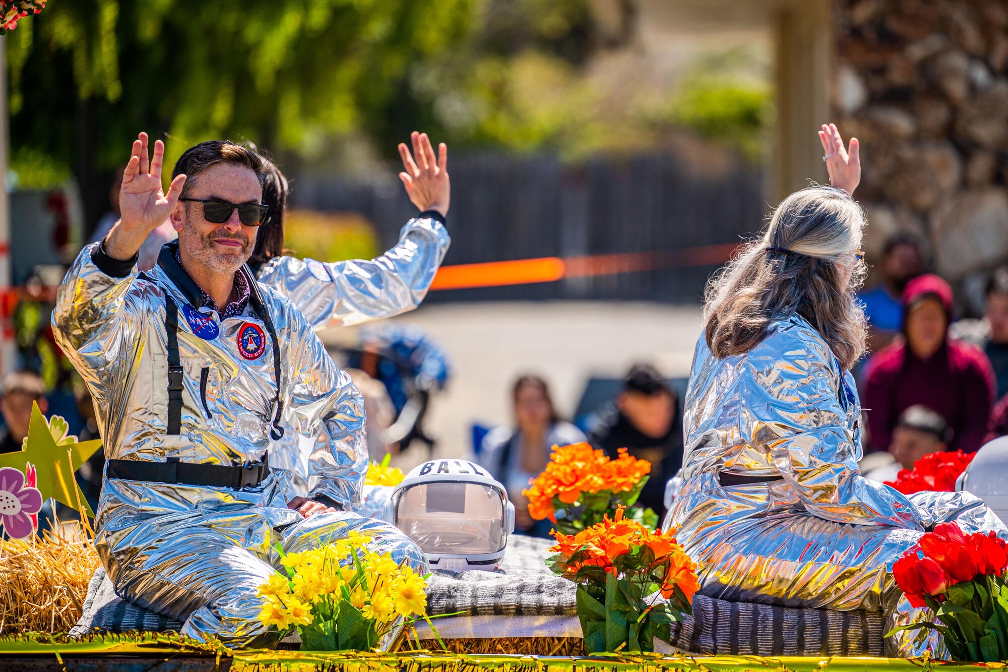 Participants dressed in space suits wave to the crowd during the Lompoc Flower Festival Parade in Lompoc, Calif., June 22, 2024. Leadership from U.S. Space Forces - Space and Space Launch Delta 30 participated in the parade which had over 50 entrees and 500 attendees. (U.S. Space Force photo by Tech. Sgt. Luke Kitterman)