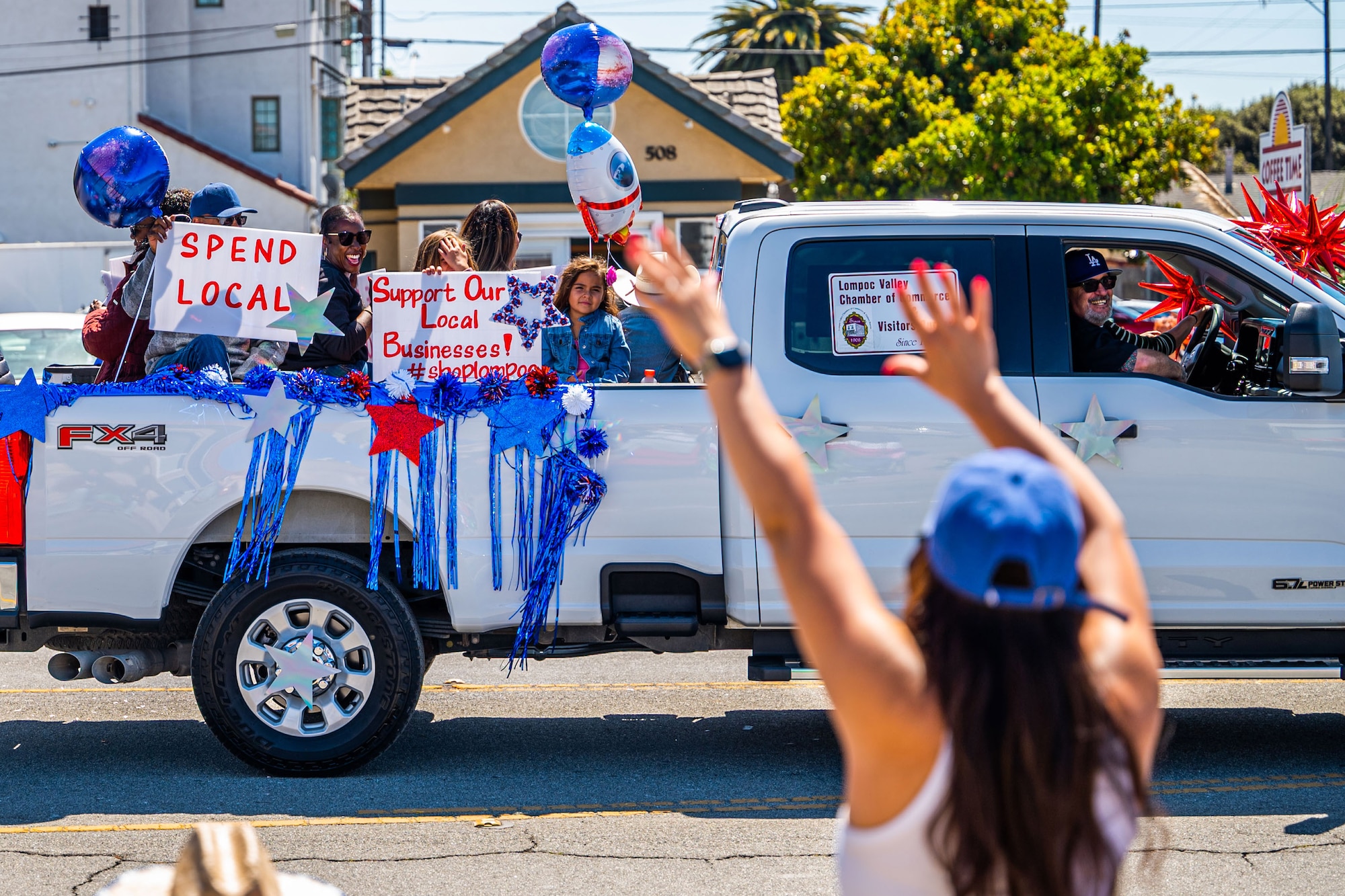 An attendee of a parade wave to participants during the Lompoc Flower Festival Parade in Lompoc, Calif., June 22, 2024. Leadership from U.S. Space Forces - Space and Space Launch Delta 30 participated in the parade which had over 50 entrees and 500 attendees. (U.S. Space Force photo by Tech. Sgt. Luke Kitterman)