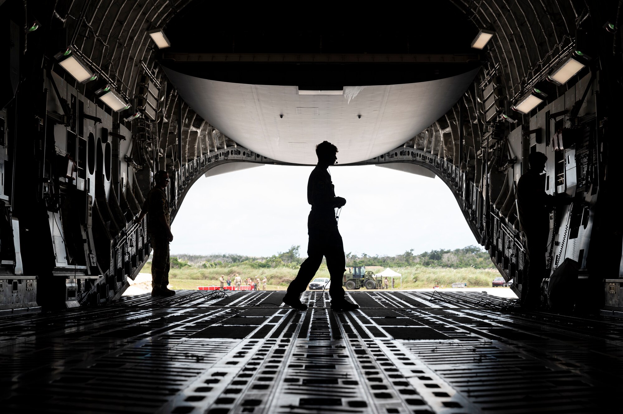 U.S. Air Force Senior Airman Ian Allen, 305th Aircraft Maintenance Squadron (AMXS) flying crew chief, left, Airman 1st Class Logan Long, middle, and Senior Airman Braden Russel, right, 6th Airlift Squadron (AS) loadmasters, lower the ramp on a U.S. Air Force C-17 Globemaster III at an auxiliary field near Anderson Air Force Base, Guam in support of Valiant Shield 2024 June 10, 2024. Specialized fueling operations increase flexibility for mobility aircraft to maneuver the joint force. Exercises such as Valiant Shield allow the Indo-Pacific Command Joint Forces the opportunity to integrate forces from all branches of service and with our allies to conduct precise, lethal, and overwhelming multi-axis, multi-domain effects that demonstrate the strength and versatility of the Joint Force and our commitment to a free and open Indo-Pacific. (U.S. Air Force photo by Senior Airman Keegan Putman)