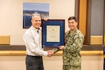 Capt. JD Crinklaw, commander, Puget Sound Naval Shipyard & Intermediate Maintenance Facility, presents Marc Harrington, former nuclear engineering and planning manager, Code 2300, Nuclear Engineering and Planning, the Navy Meritorious Civilian Service Award, May 31, 2024, during his retirement ceremony at the Olympic Lodge on Naval Base Kitsap in Bremerton, Washington. (U.S. Navy photo by Jeb Fach)