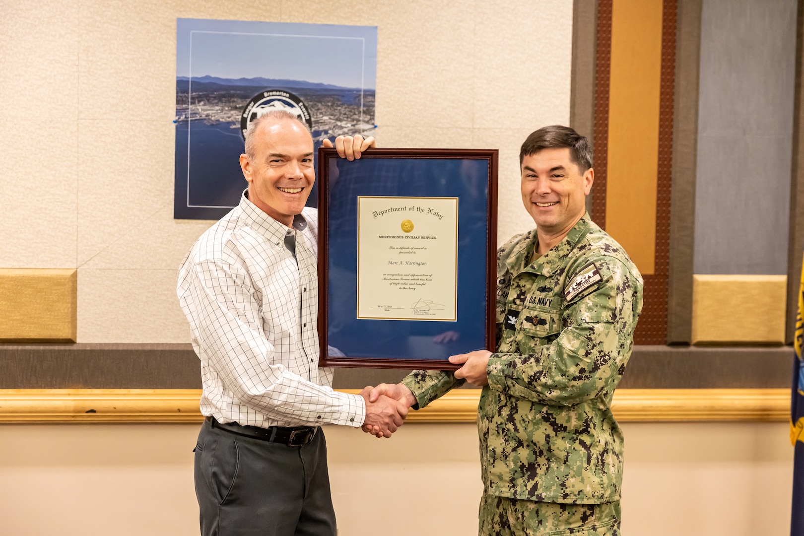 Capt. JD Crinklaw, commander, Puget Sound Naval Shipyard & Intermediate Maintenance Facility, presents Marc Harrington, former nuclear engineering and planning manager, Code 2300, Nuclear Engineering and Planning, the Navy Meritorious Civilian Service Award, May 31, 2024, during his retirement ceremony at the Olympic Lodge on Naval Base Kitsap in Bremerton, Washington. (U.S. Navy photo by Jeb Fach)