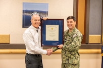 Capt. JD Crinklaw, commander, Puget Sound Naval Shipyard & Intermediate Maintenance Facility, presents Marc Harrington, former nuclear engineering and planning manager, Code 2300, Nuclear Engineering and Planning, the Navy Meritorious Civilian Service Award, May 31, 2024, during his retirement ceremony at the Olympic Lodge on Naval Base Kitsap in Bremerton, Washington. (U.S. Navy photo by Jeb Fach)