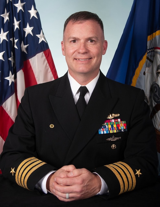 CAPT G. Reed Koepp II, Joint Base Charleston deputy commander, Naval Support Activity commander in full service uniform, in front of US. flag and U.S. Navy flag.