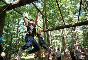 Two cadets swing across monkey bars during a base tour