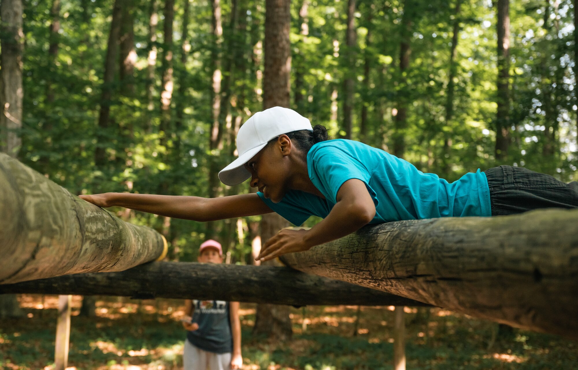 A cadet pulls herself across logs on an obstacle course