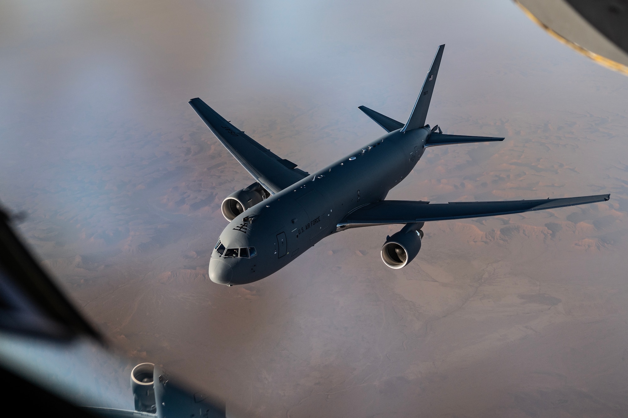 A U.S. Air Force KC-46 Pegasus from McConnell Air Force Base's 22nd Air Refueling Wing, departs after flying in formation with a KC-135 Stratotanker from McConnell Air Force Base's 350th Expeditionary Air Refueling Squadron, over the U.S. Central Command area of responsibility, July 1, 2024. The KC-46 is participating in Project Magellan, a 43-hour long max endurance mission, circumnavigating the globe. The mission is the longest sortie in AMC History and the longest combat sortie in history. (U.S. Air Force photo)