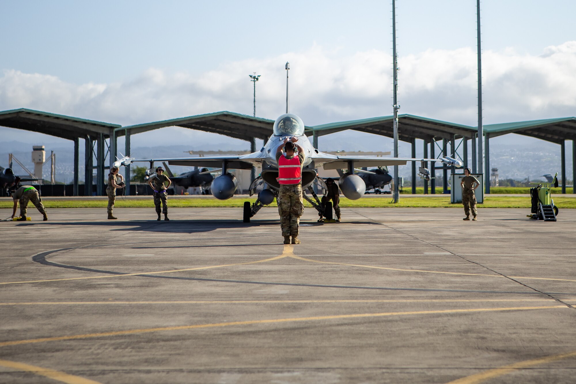 A U.S. Air Force 177th Aircraft Maintenance Squadron (AMXS) crew chief signals an F-16 Fighting Falcon fighter jet pilot from the 177th Fighter Wing, New Jersey Air National Guard, to hold prior to takeoff, along with other 177th AMXS members, at Joint Base Pearl Harbor-Hickam, Hawaii, June 5, 2024.