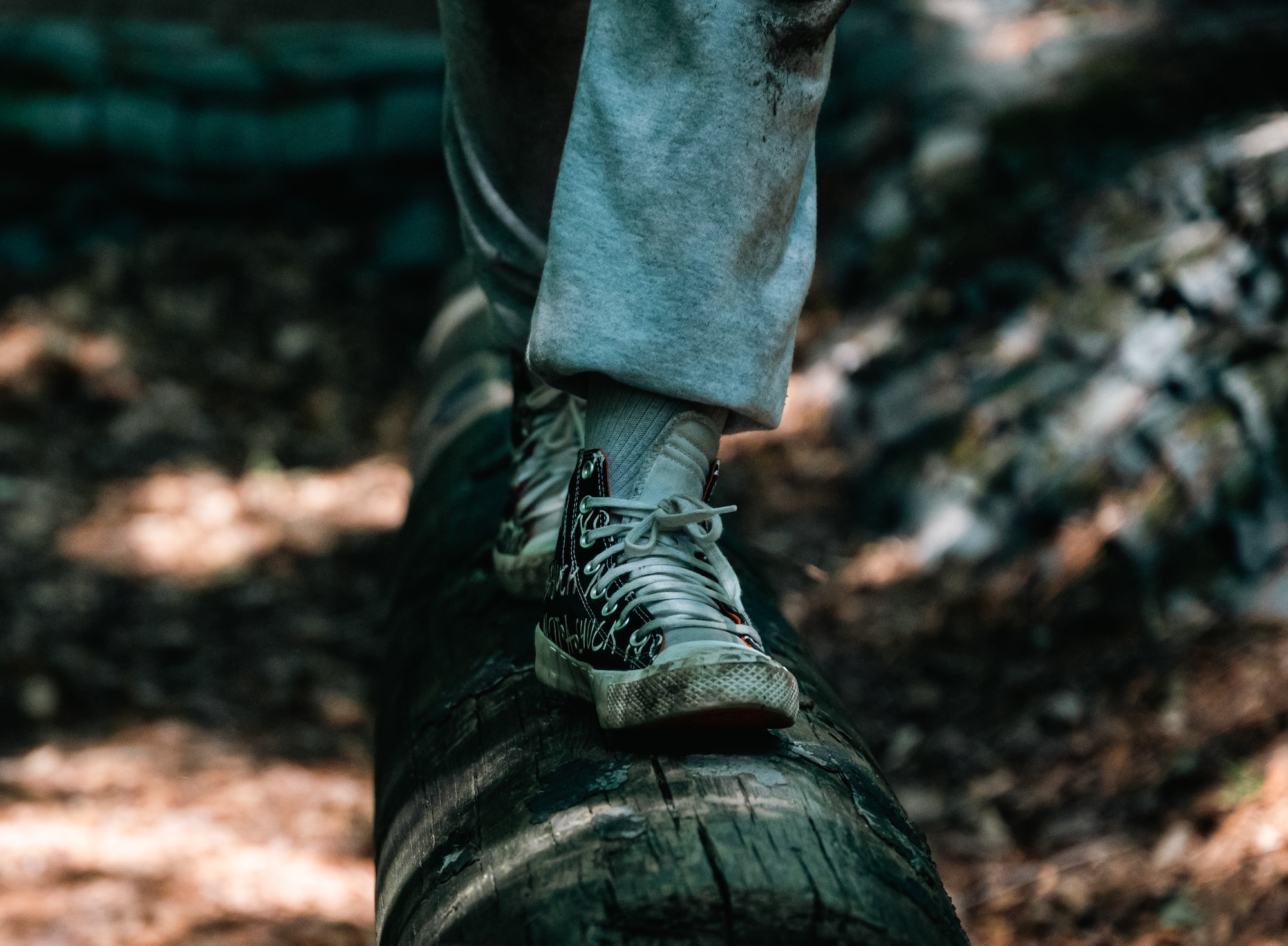 A pair of dirty converse walk across a log