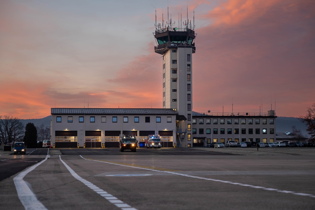 A pink sky hints at the rising sun behind a building with a control tower.