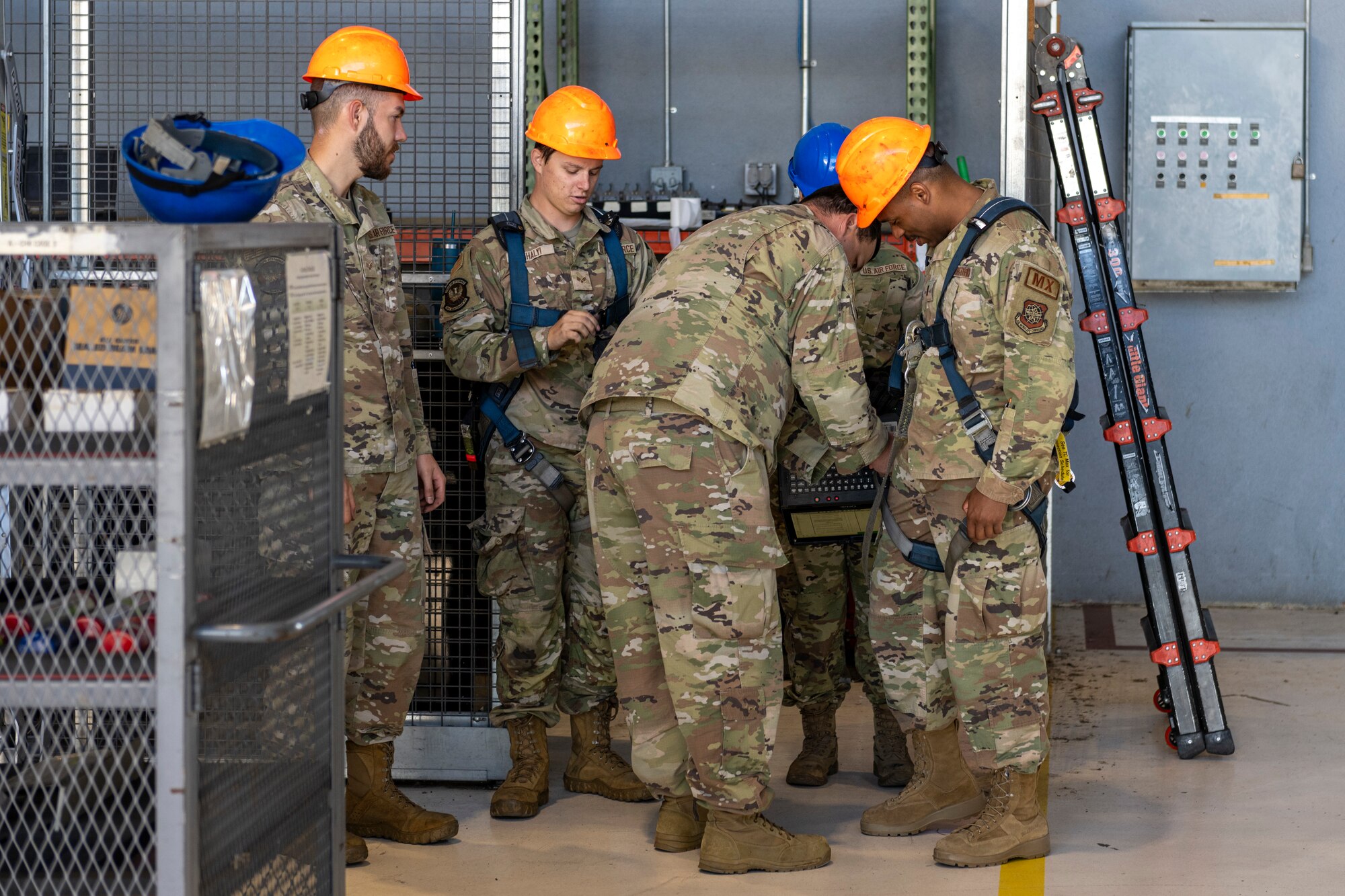 Airmen put on safety gear to go on a tail stand