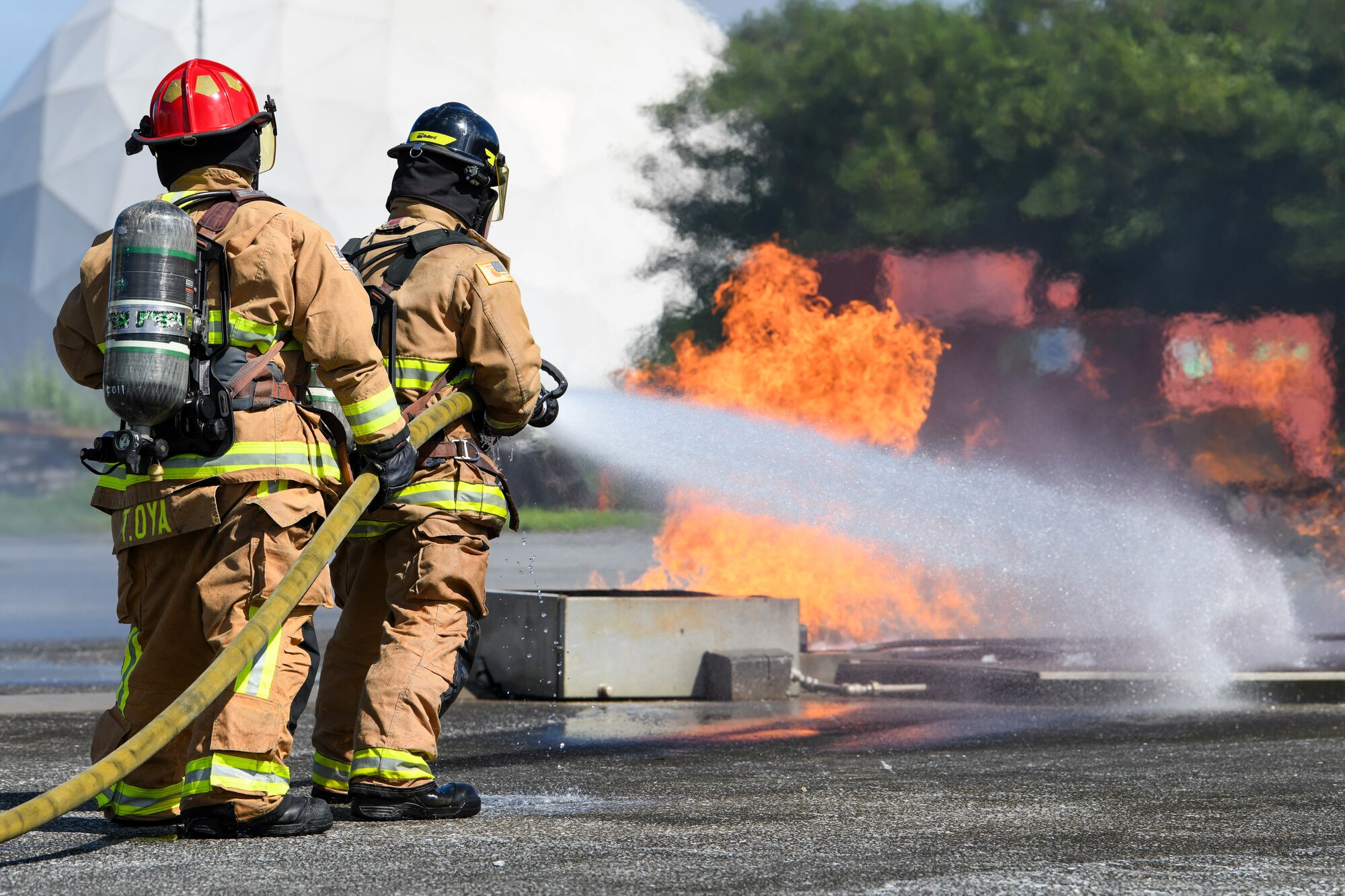 Two Kadena firefighters work together to put out a simulated oil fire