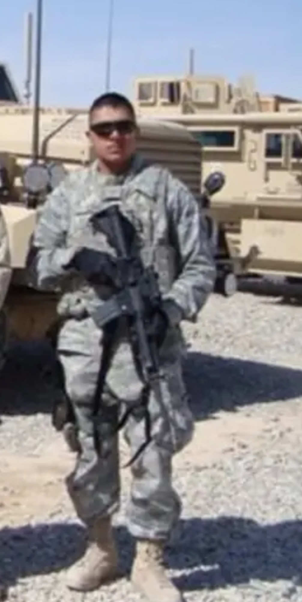 Individual in uniform poses for a photo in the Afghanistan dessert.