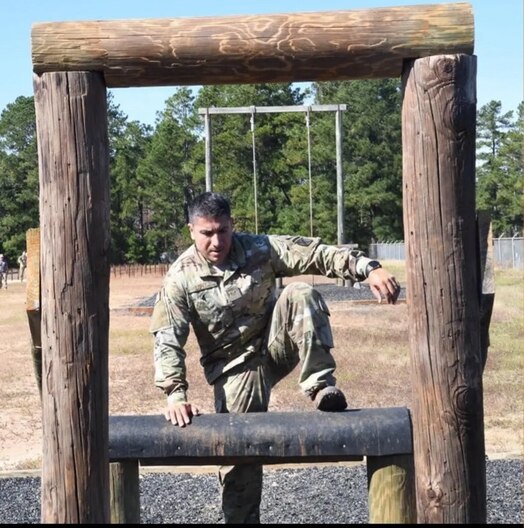  Individual in uniform jumps over an obstacle course.