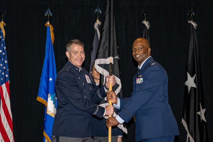 Maj. Gen. Gregory Gagnon, deputy chief of Space Operations for Intelligence, passes Col. Marcus Starks, incoming National Space Intelligence Center commander, the guidon during a change of command ceremony at Wright-Patterson Air Force Base, June 28, 2024. The historic event was the first NSIC change of command ceremony as well as the activation of the unit as a field operating agency reporting directly to headquarters U.S. Space Force. (U.S. Air Force photo by Daniel Peterson)