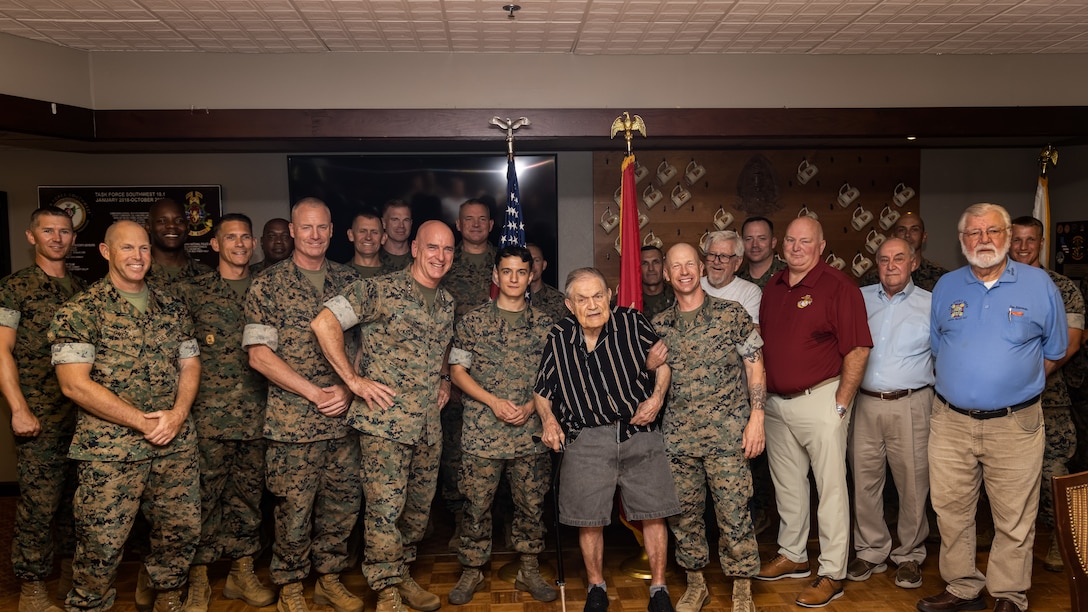 U.S. Marines and civilians with II Marine Expeditionary Force stand for a group photo with 98-year-old U.S. Marine Corps veteran Charles “Chester” Clapper during a celebration in his honor at Marine Corps Base Camp Lejeune, N.C., June 12, 2024. Clapper was drafted into military service in 1943 and served as a flame thrower during the Battle of Iwo Jima, being one of seven surviving members of his company following the battle. (U.S. Marine Corps Photo by Cpl. Noah Seal)