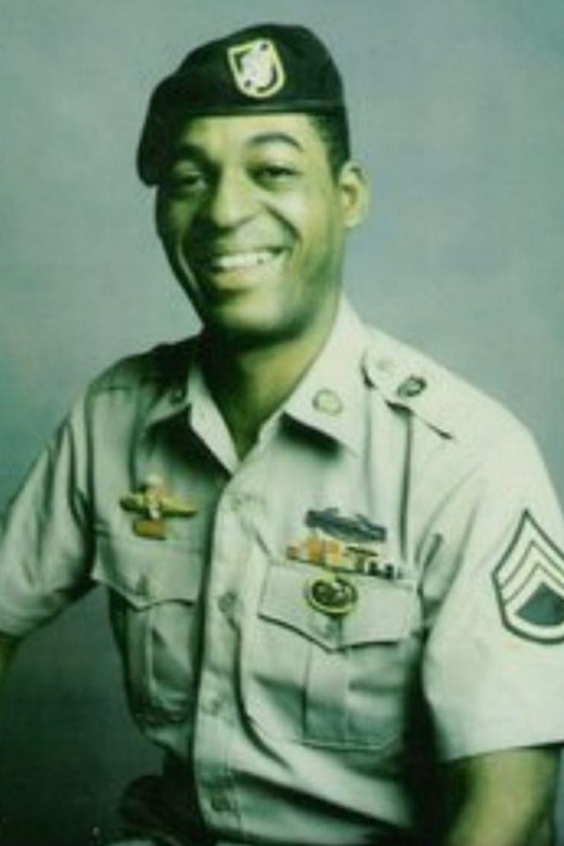 A person in a uniform and beret smiles for a photo.