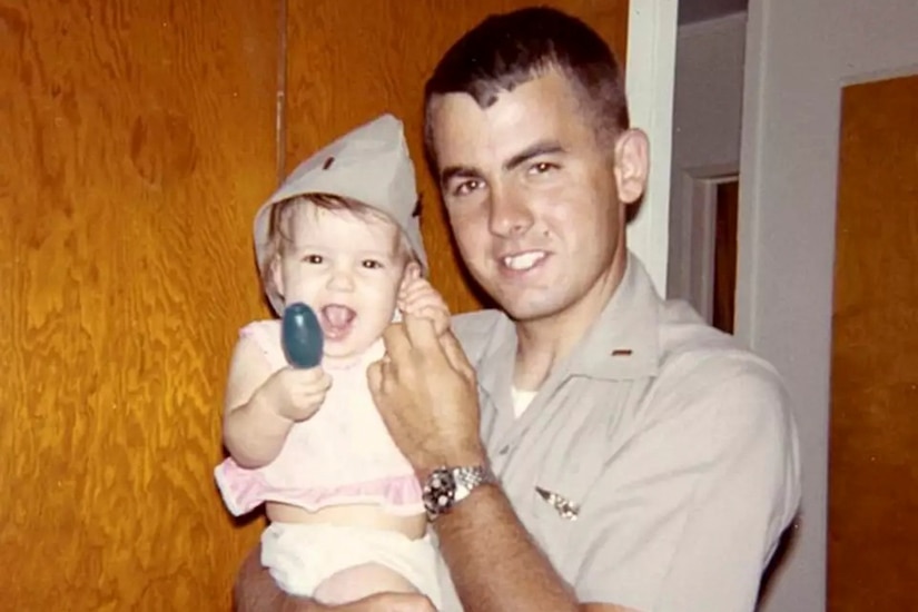 A service member holds a young child.