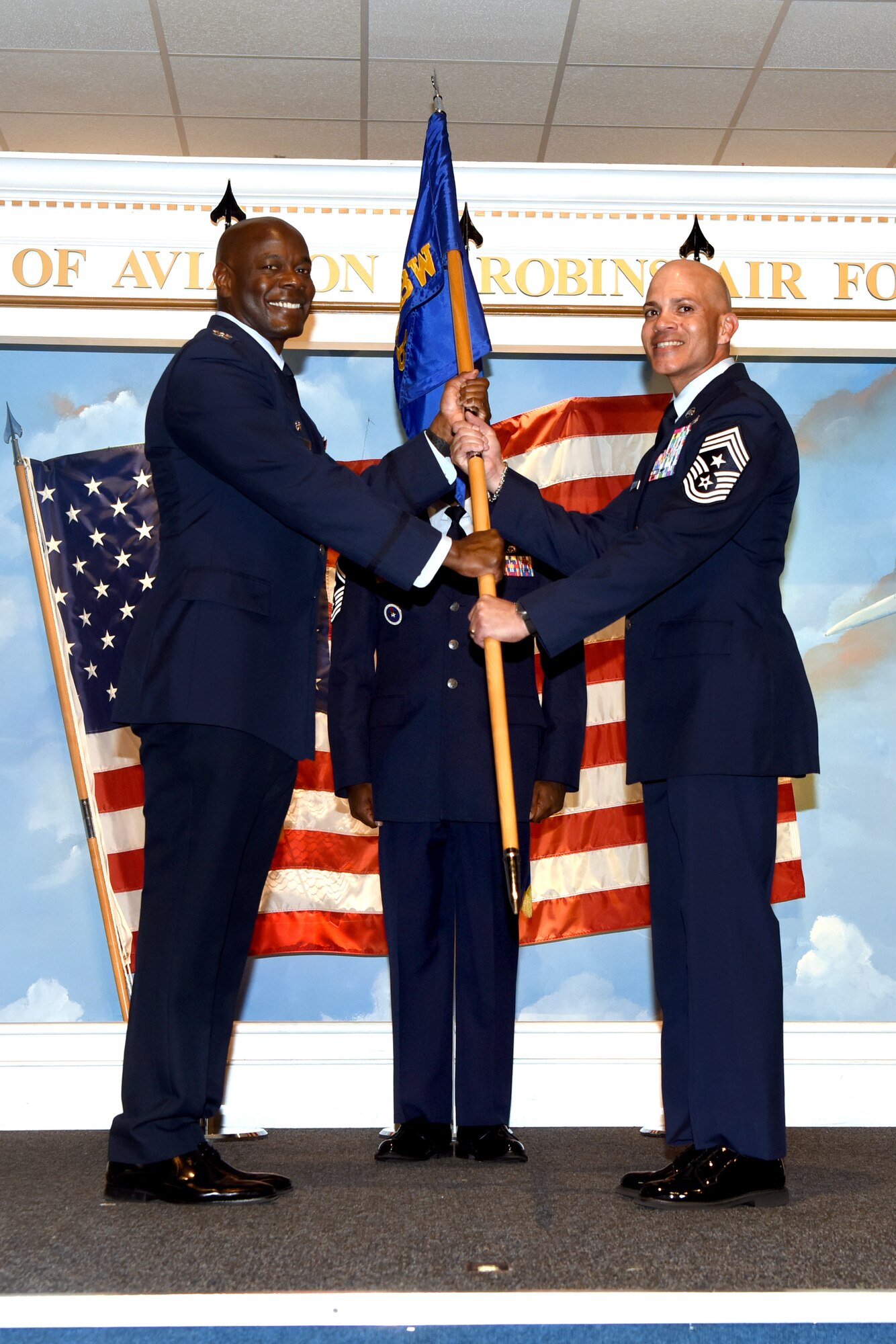 Two men in military uniform standing while holding a guidon