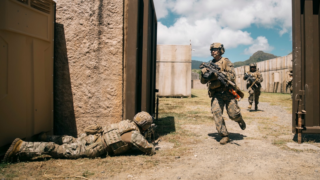 A Chilean marine assigned to 213 Tauro holds security while U.S. Marines assigned to Battalion Landing Team 1/5, 15th Marine Expeditionary Unit, egress from the infantry immersion trainer (IIT) at Marine Corps Training Area Bellows, Waimanalo, Hawaii, for Exercise Rim of the Pacific (RIMPAC) 2024, June 29. The IIT provided immersive scenario-based training to evaluate Marines and partner nations in infantry tactics. Twenty-nine nations, 40 surface ships, three submarines, 14 national land forces, more than 150 aircraft, and 25,000 personnel are participating in and around the Hawaiian Islands, June 27 to Aug. 1. The world’s largest international maritime exercise; RIMPAC provides a unique training opportunity while fostering and sustaining cooperative relationships among participants critical to ensuring the safety of sea lanes and security on the world’s oceans. RIMPAC 2024 is the 29th exercise in the series that began in 1971. (U.S. Marine Corps photo by Cpl. Joseph Helms)