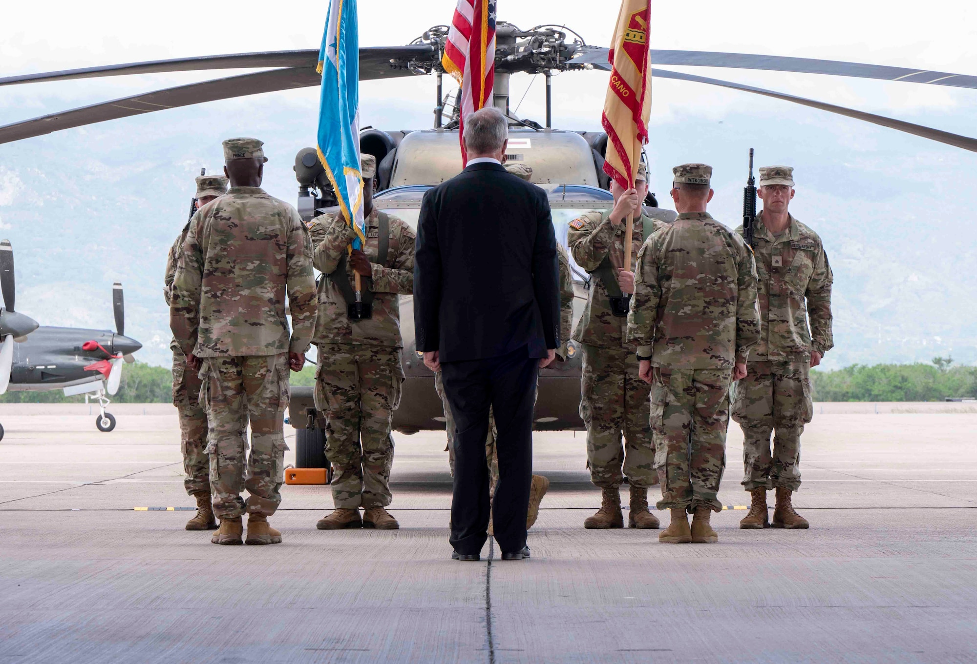 A group of people standing waiting to pass a guidon to each other.