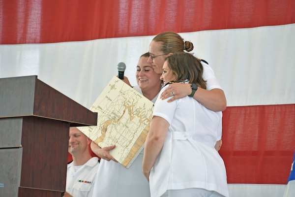 JACKSONVILLE, Fla. (June 28, 2024) – Guest Speaker Lt. Cmdr. Emily Goodwin, from the left, receives hugs from Family Medicine Residency Program Chiefs Lt. Chelsey Haley and Lt. Bristal Thompson during the graduation ceremony June 28 onboard Naval Air Station Jacksonville.  Goodwin, who is a current faculty member spoke about growth she has seen during her three years with the group. U.S. Navy Photo by Julie M. Lucas