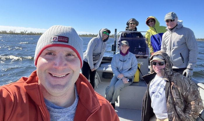7 people smiling at the camera with the bay in the background