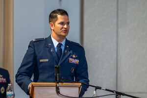 A man in a blue uniform speaks at a podium.