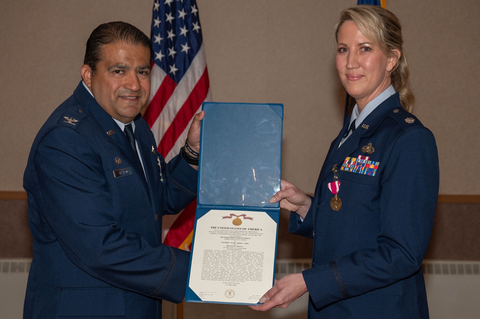 U.S. Air Force Col. Antonio Alvarado (left), 354th Mission Support Group commander, hands a Meritorious Service Medal certificate to Lt. Col. Amanda Henry, 354th Force Support Squadron outgoing commander, at Eielson Air Force Base, Alaska, July 2, 2024.