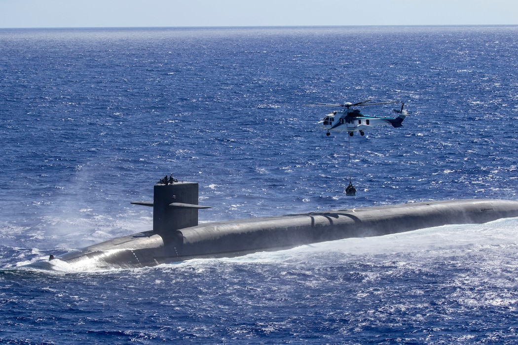 An AS-332 Super Puma assigned to the Lewis and Clark-class dry cargo ship  USNS Cesar Chavez (T-AKE 14) delivers supplies to the Ohio-class ballistic missile submarine USS Louisiana (SSBN 743) during a vertical replenishment at sea, June 28, 2024.