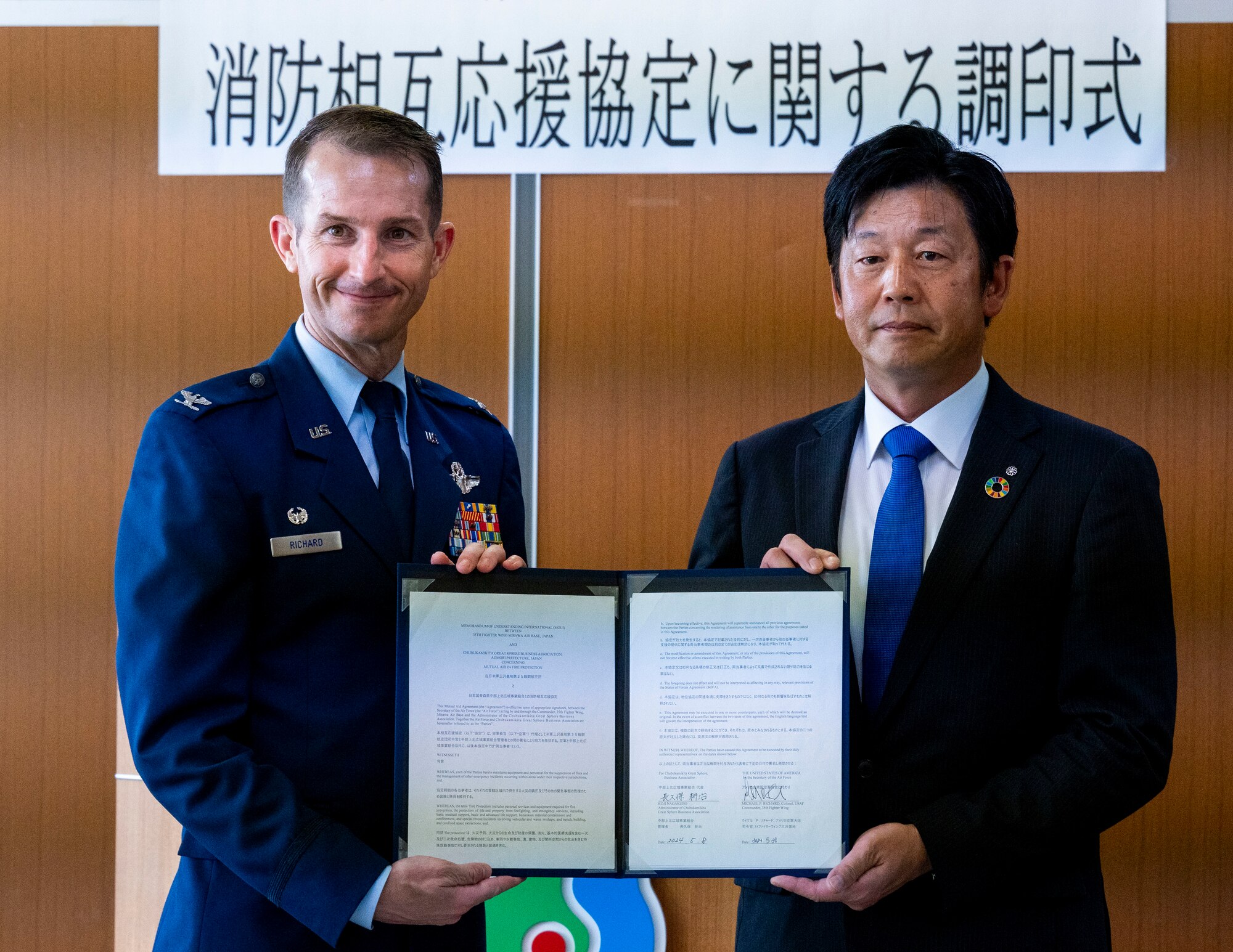 U.S. Air Force Col. Michael Richard, left, 35th Fighter Wing commander, and Mr. Koji Nagakubo, right, Tohuko Town mayor, pose with the signed copy of the Memorandum of Understanding International (MoUI) during the Fire Protection Agreement ceremony at Tohoku Town, Japan, July 1, 2024.