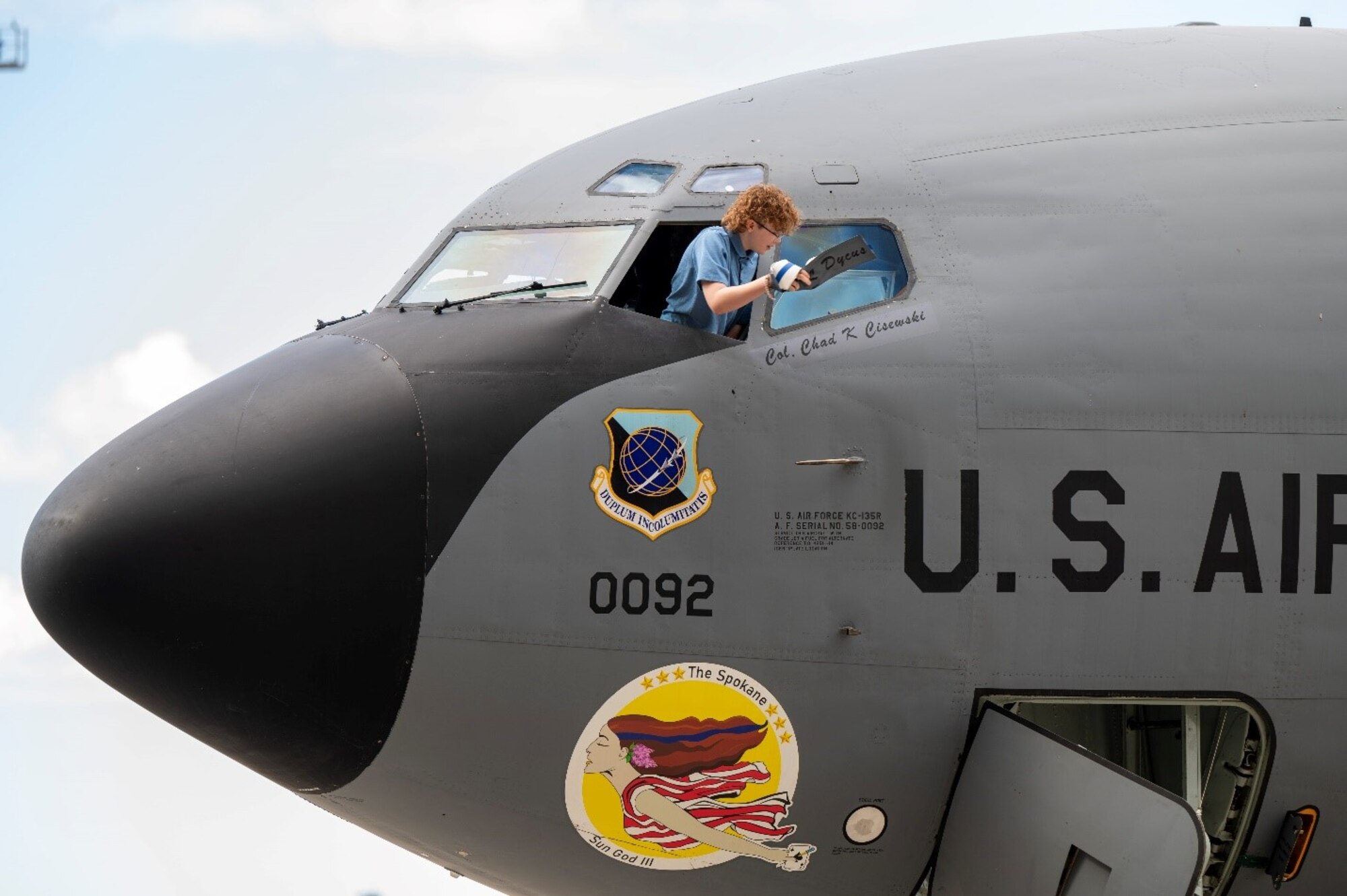 A military child removes a nametag on an airplane